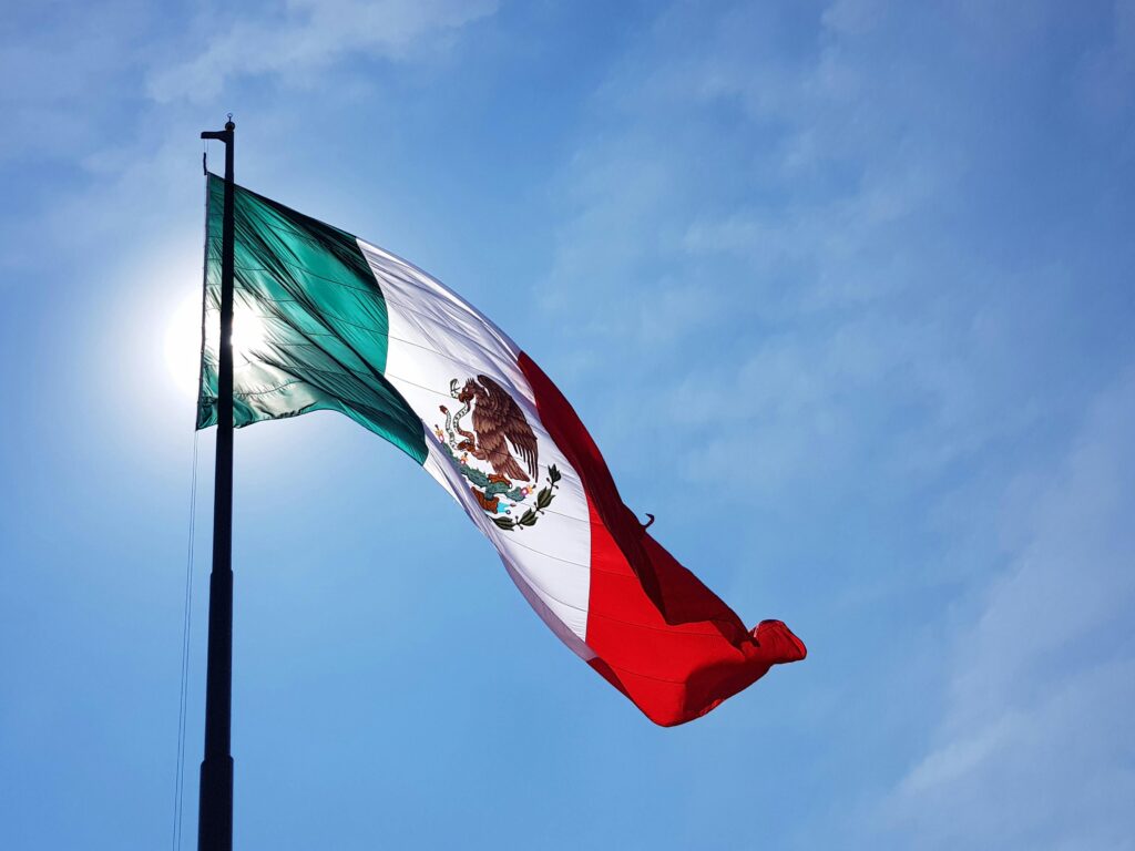 Mexican national flag standing proudly in the clear blue sky, tailing in the wind.
